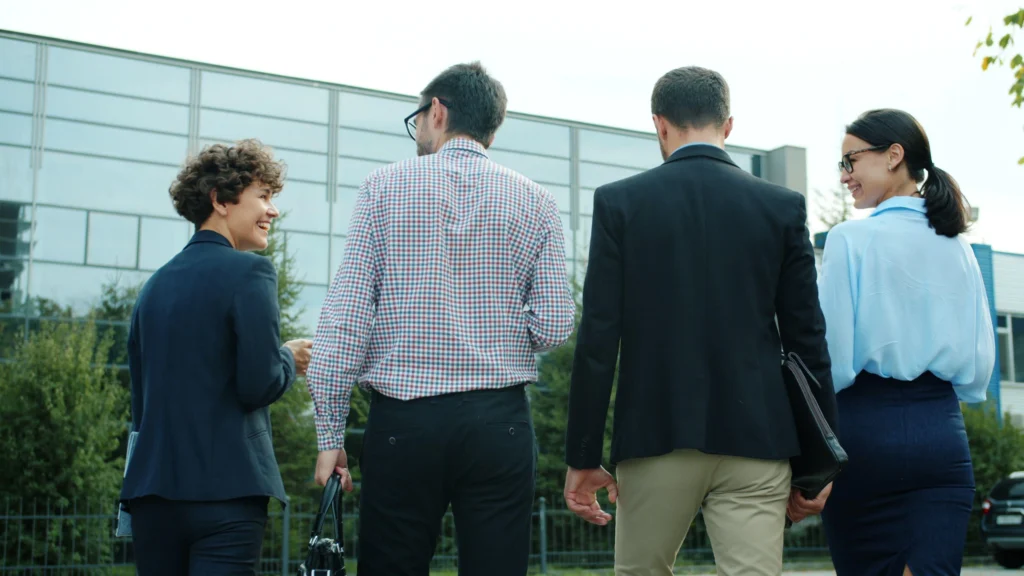 Group of four business professionals walking and talking outside an office building