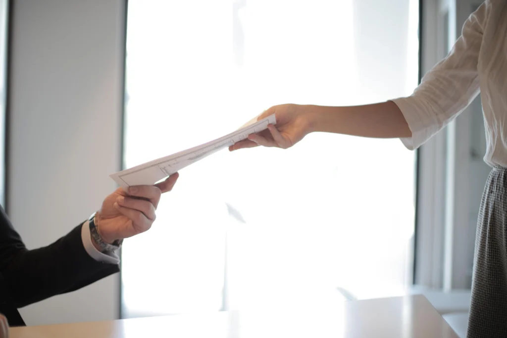 Recruiter handing a document to a job seeker during a recruitment consultation