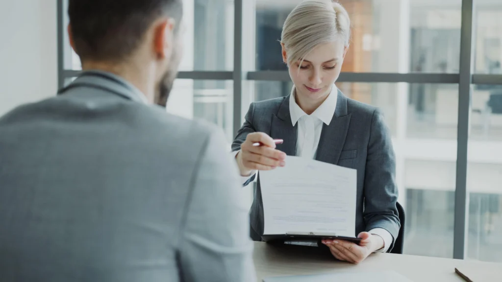 Recruitment consultant reviewing a job contract with a candidate in an office meeting